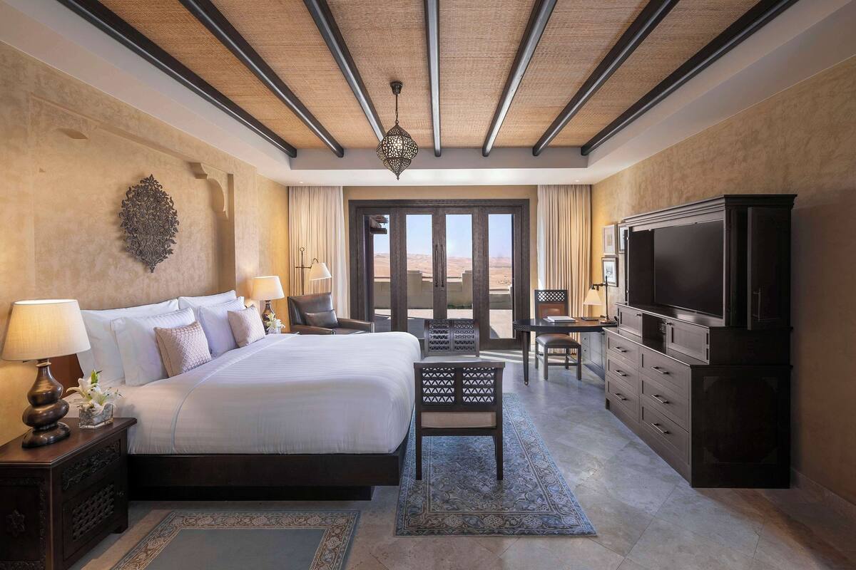 A spacious bedroom with a large bed, a television, and a desk with a chair.