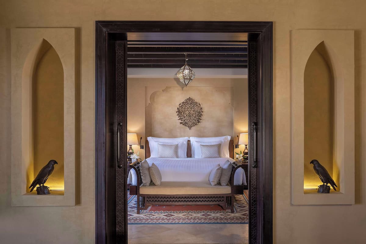 A bedroom with a bed, a decorative wall hanging, and two wall-mounted bird sculptures.