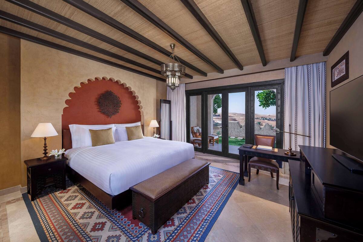 A spacious bedroom with a large bed, a desk, and a view of the outdoors.