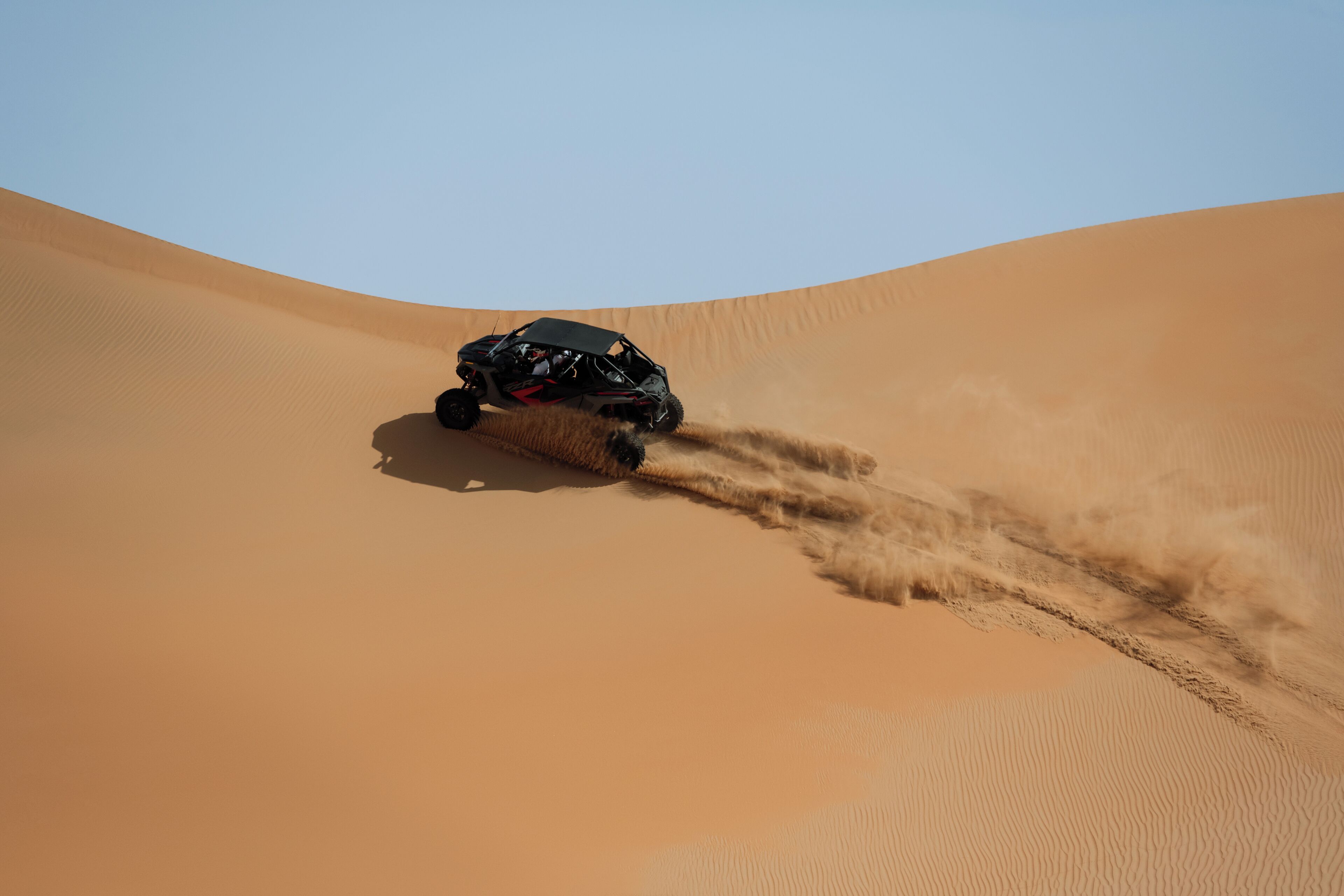 Ein Fahrzeug bewegt sich über eine Sanddüne.