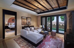 Habitación de hotel con una cama grande, un sofá, una mesa de centro y vistas al exterior.