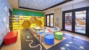 A children's play area with colorful furniture, a play mat, and a bookshelf. - Qasr Al Sarab Desert Resort by Anantara (Al Mirayr)