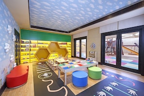 A children's play area with colorful furniture, a play mat, and a bookshelf. - Qasr Al Sarab Desert Resort by Anantara (Al Mirayr)