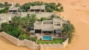 Un resort en el desierto con varias villas, piscina y abundante vegetación.