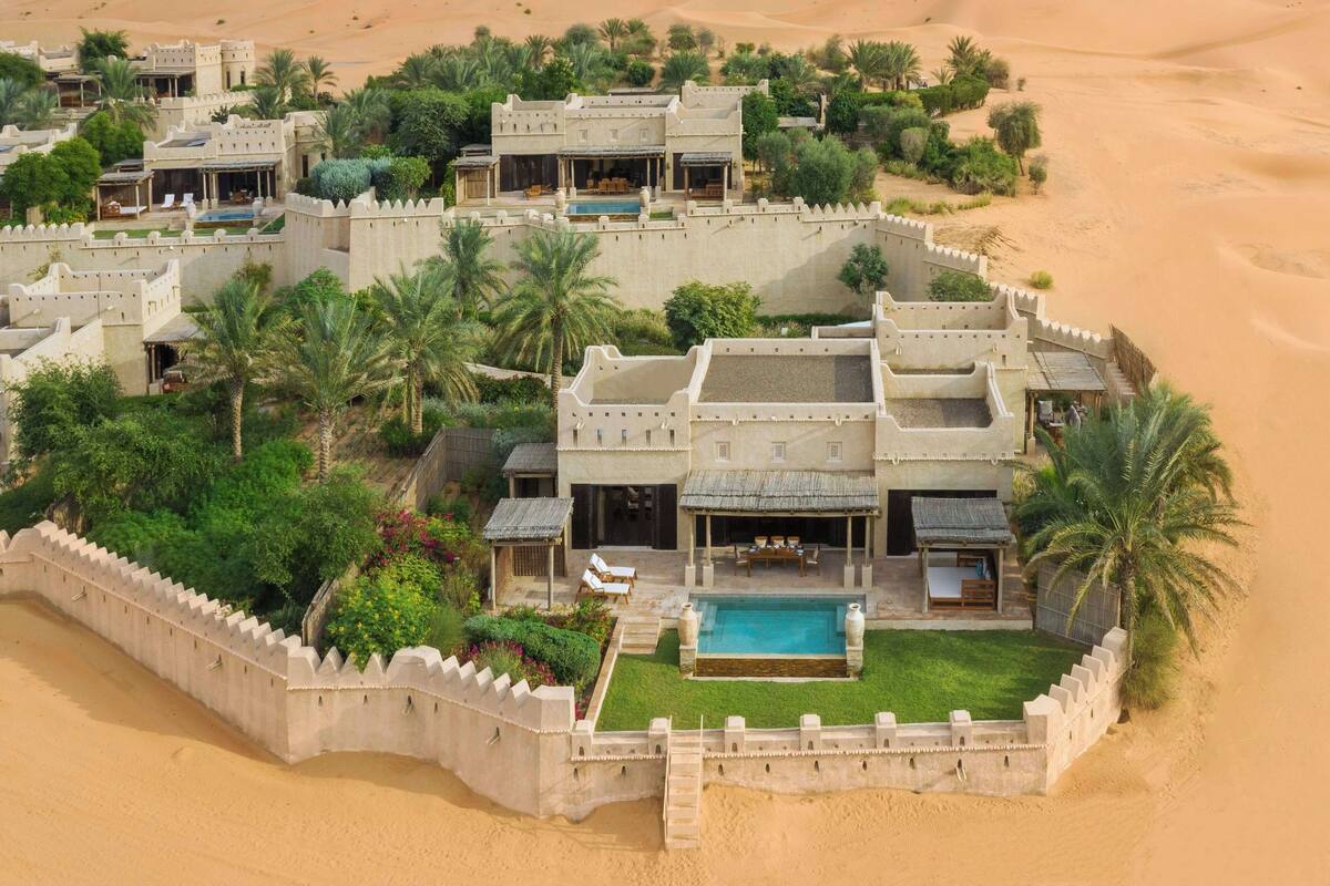 A desert resort with multiple villas, a swimming pool, and lush greenery.