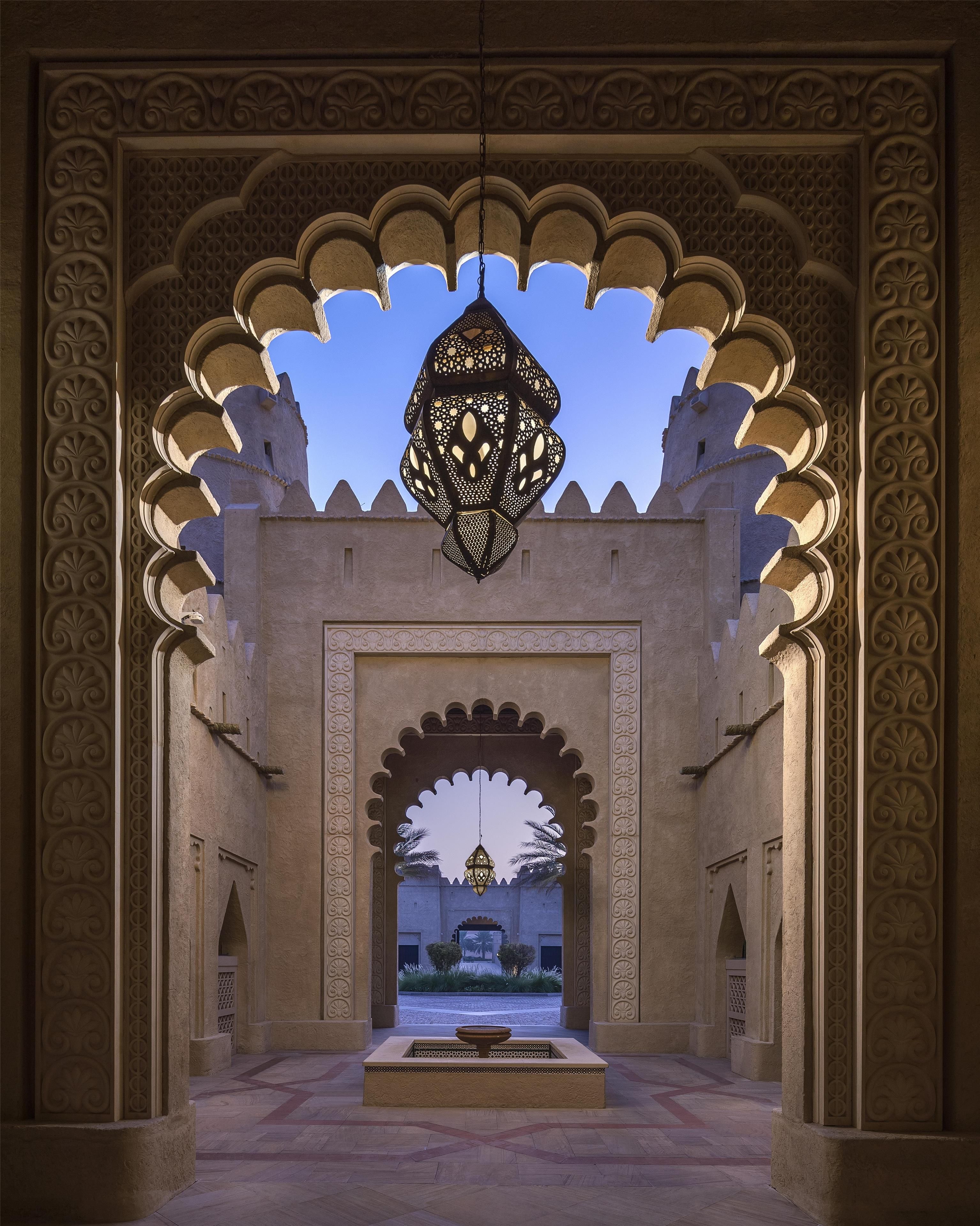 An ornate archway with intricate carvings and a hanging lantern.