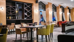 Un restaurante con mesas, sillas, una cava de vinos y vistas a la ciudad.