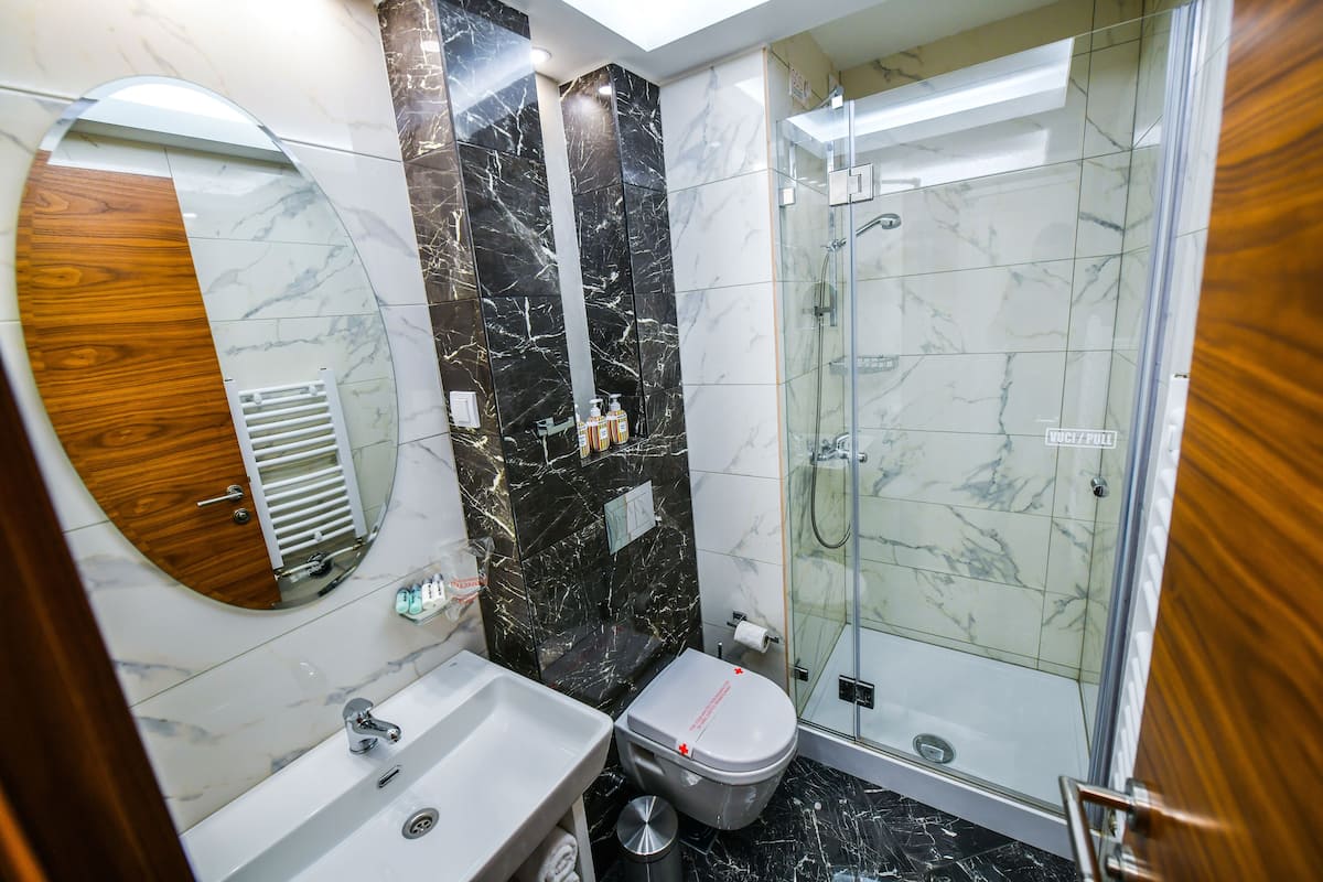 A modern bathroom with a marble vanity, a toilet, and a glass-enclosed shower.