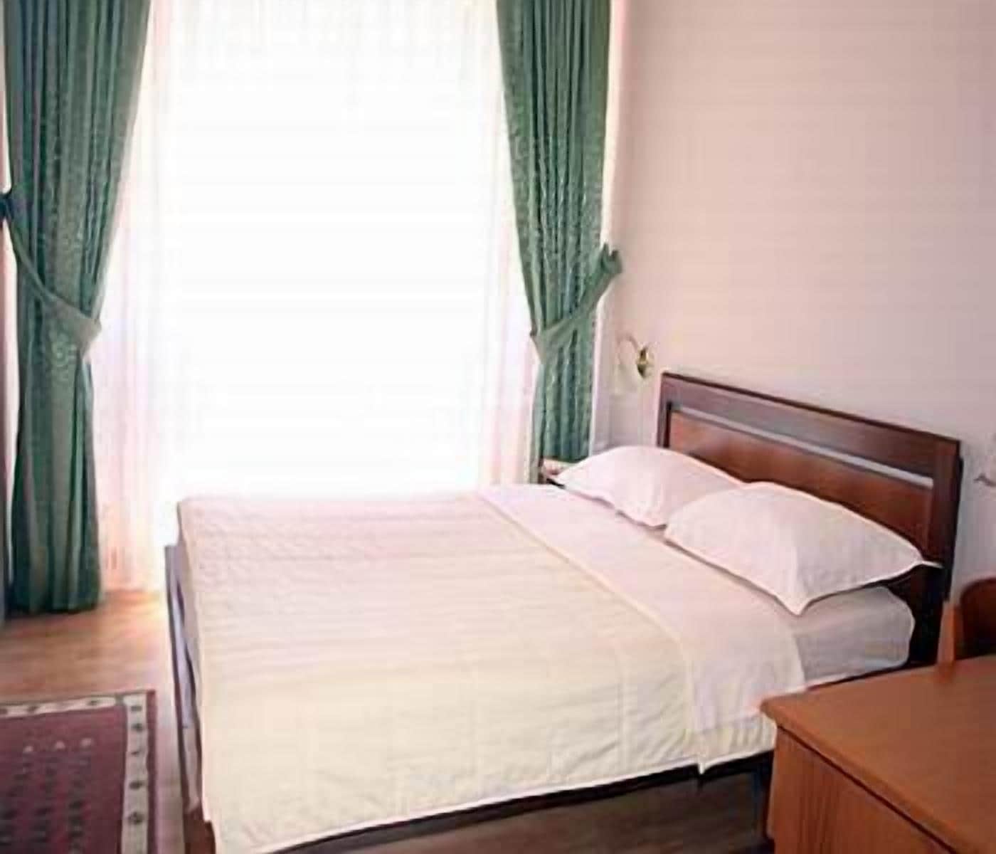 A neatly made bed with white linens in a room with a wooden headboard.