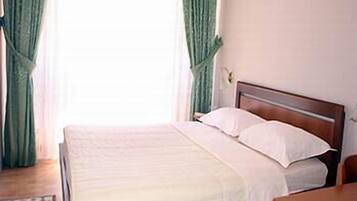 A neatly made bed with white linens in a room with a wooden headboard.
