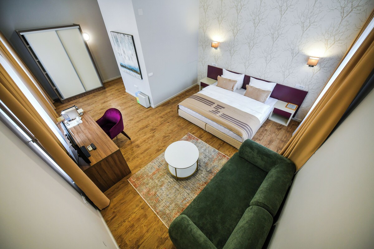 A hotel room with a bed, a desk, a chair, a round table, and a sofa.