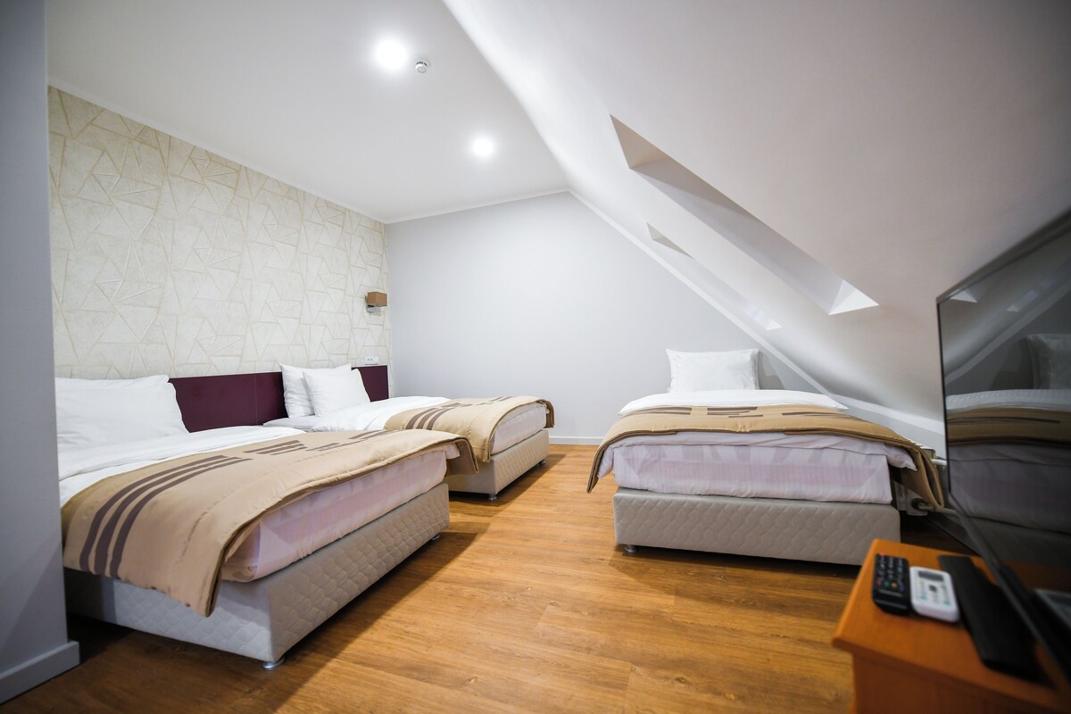 A modern hotel room with two beds, a wooden floor, and a small desk with a phone.