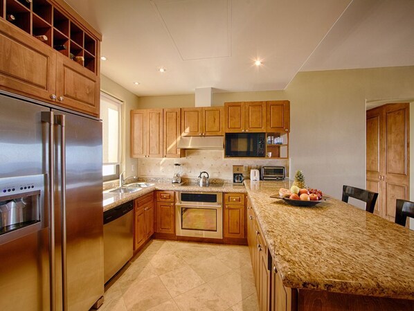 A modern kitchen with wooden cabinets, stainless steel appliances, and a granite countertop.