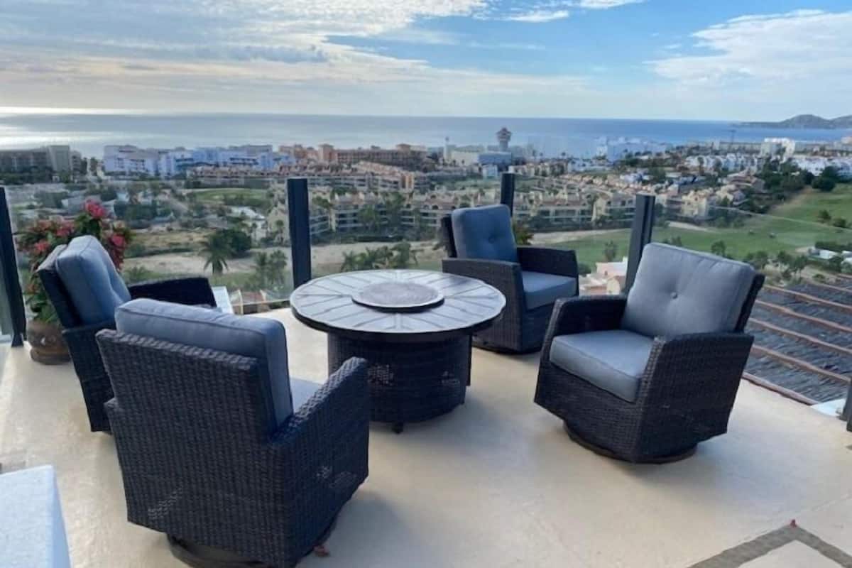 Un balcon agrémenté de meubles en osier, d’une table ronde et offrant une vue sur le paysage urbain de la côte.