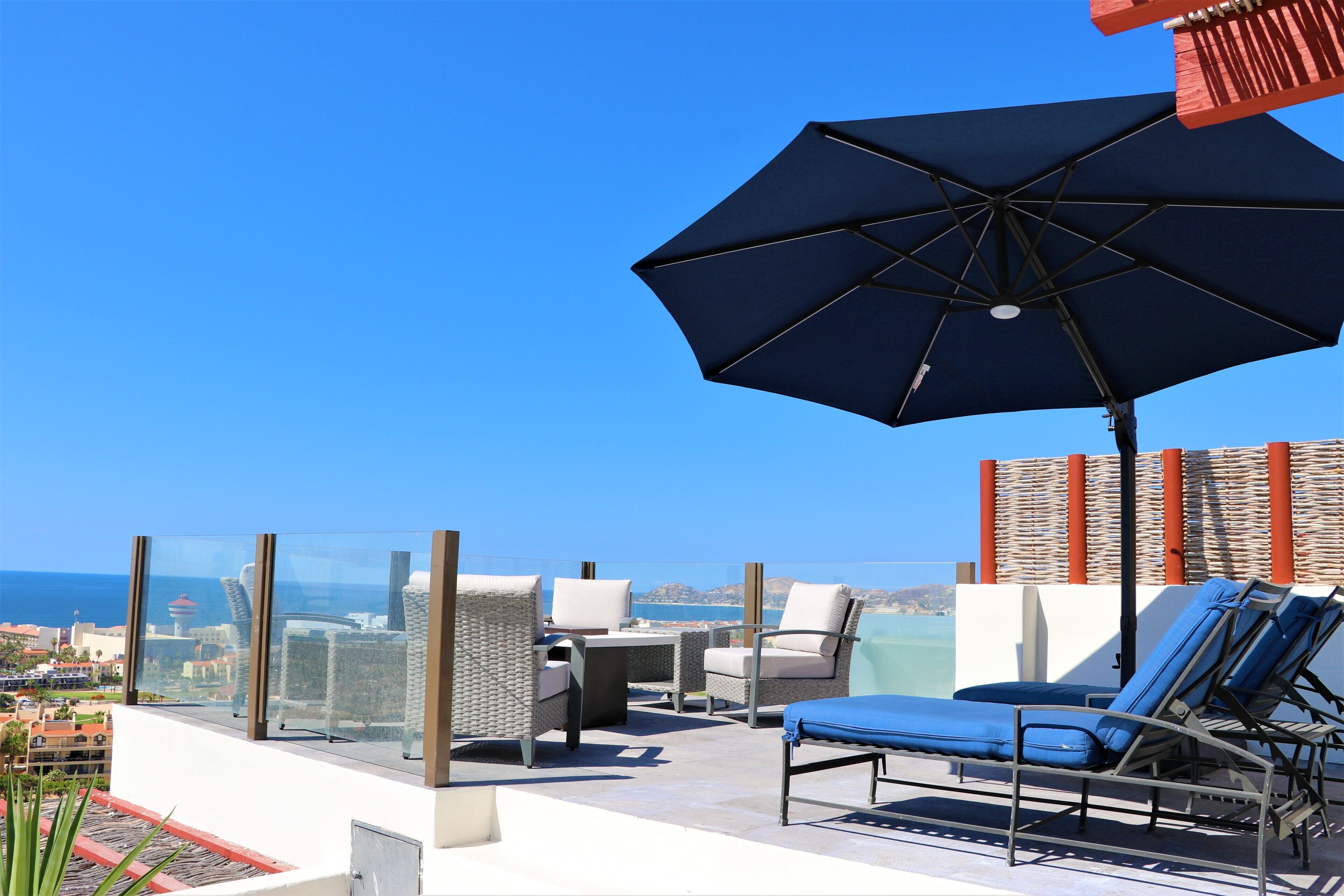 Terraza en la azotea con vistas despejadas al océano, amueblada con sillones y una mesa.