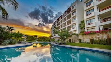 Relax by the pool surrounded by lush greenery and palm trees.