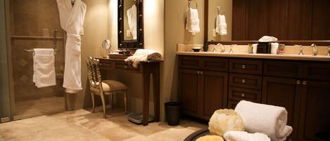 A bathroom with a vanity, a chair, a mirror, and a round table with towels.