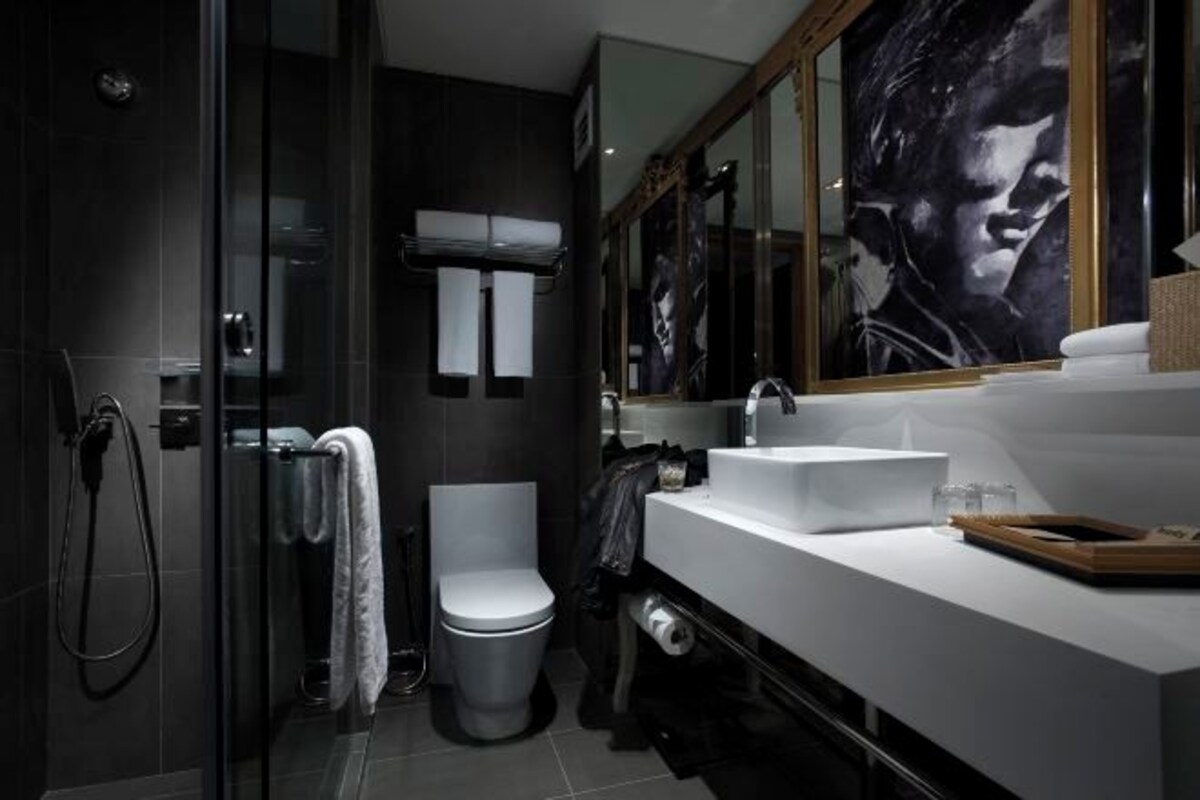 Un baño moderno con cabina de ducha de vidrio, inodoro blanco y un espejo grande sobre el lavabo.