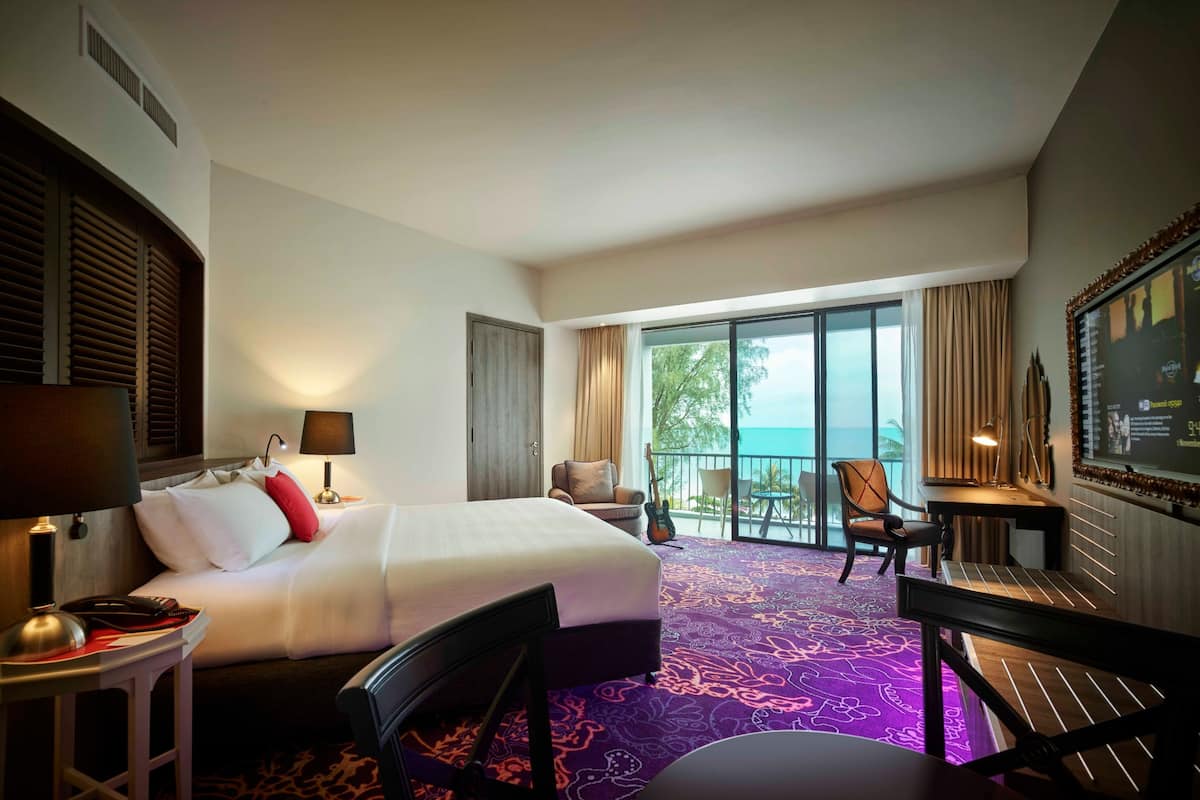A hotel room with a bed, a desk, a chair, and a balcony with a view.