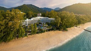 A hotel with multiple floors, surrounded by lush greenery and a beach. - Hard Rock Hotel Penang (George Town)
