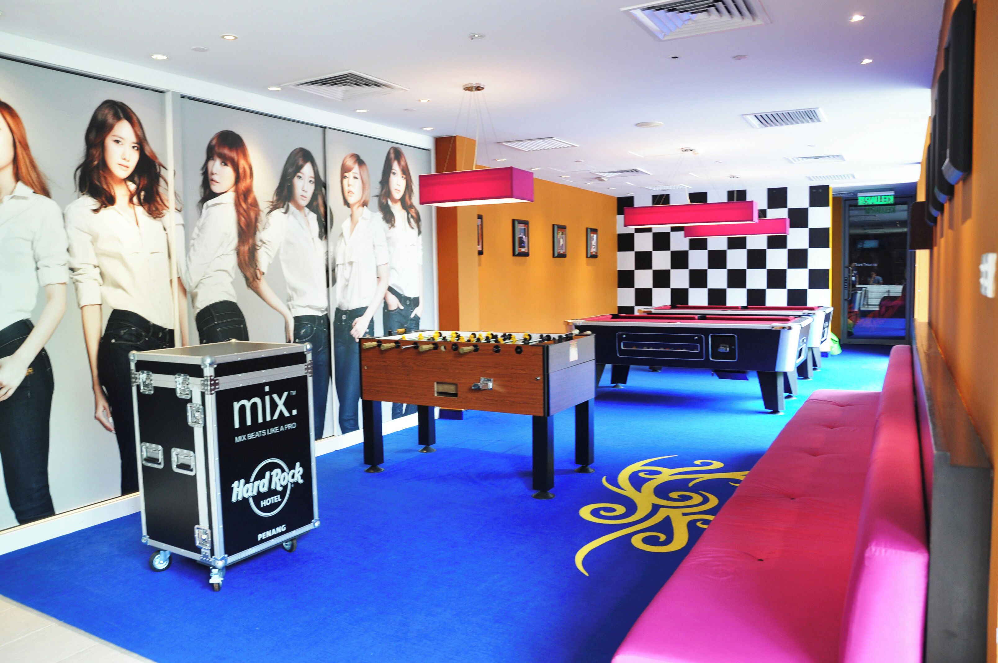 A hotel lobby with a foosball table, a jukebox, and a checkered wall.