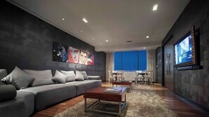Un salon moderne avec un canapé gris, une table basse en bois et un grand écran de télévision fixé au mur.