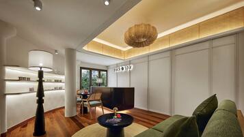 A modern living room with a sofa, a coffee table, a TV, and a lamp. There is a reception desk with a sign that reads "rock spa".