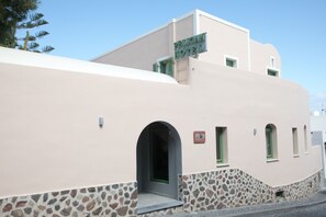 A building with a sign reading "Pelican Hotel." It features a stone base, a flat roof, and a small entrance with a green door.