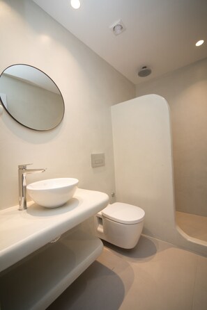 A modern bathroom with a white sink, toilet, and a large mirror.