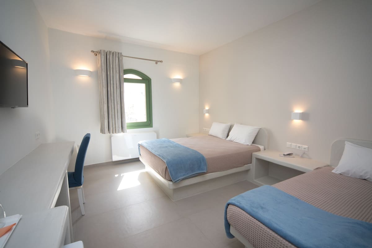 A hotel room with two beds, a desk, and a television.
