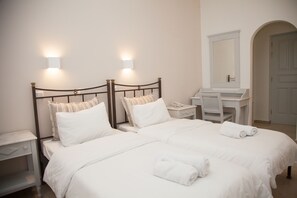 A hotel room with a double bed, bedside tables, a desk, a mirror, and a bathroom vanity.