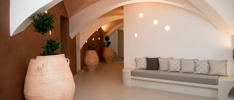 A modern interior with a curved white bench, large terracotta pots, and a minimalist design.