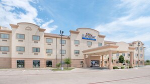 A hotel with a large entrance, multiple windows, and a clear sky. - Baymont by Wyndham Snyder (Snyder)