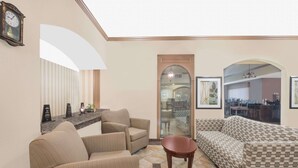 A living room with a sofa, armchairs, a coffee table, and a clock on the wall. - Baymont by Wyndham Snyder (Snyder)