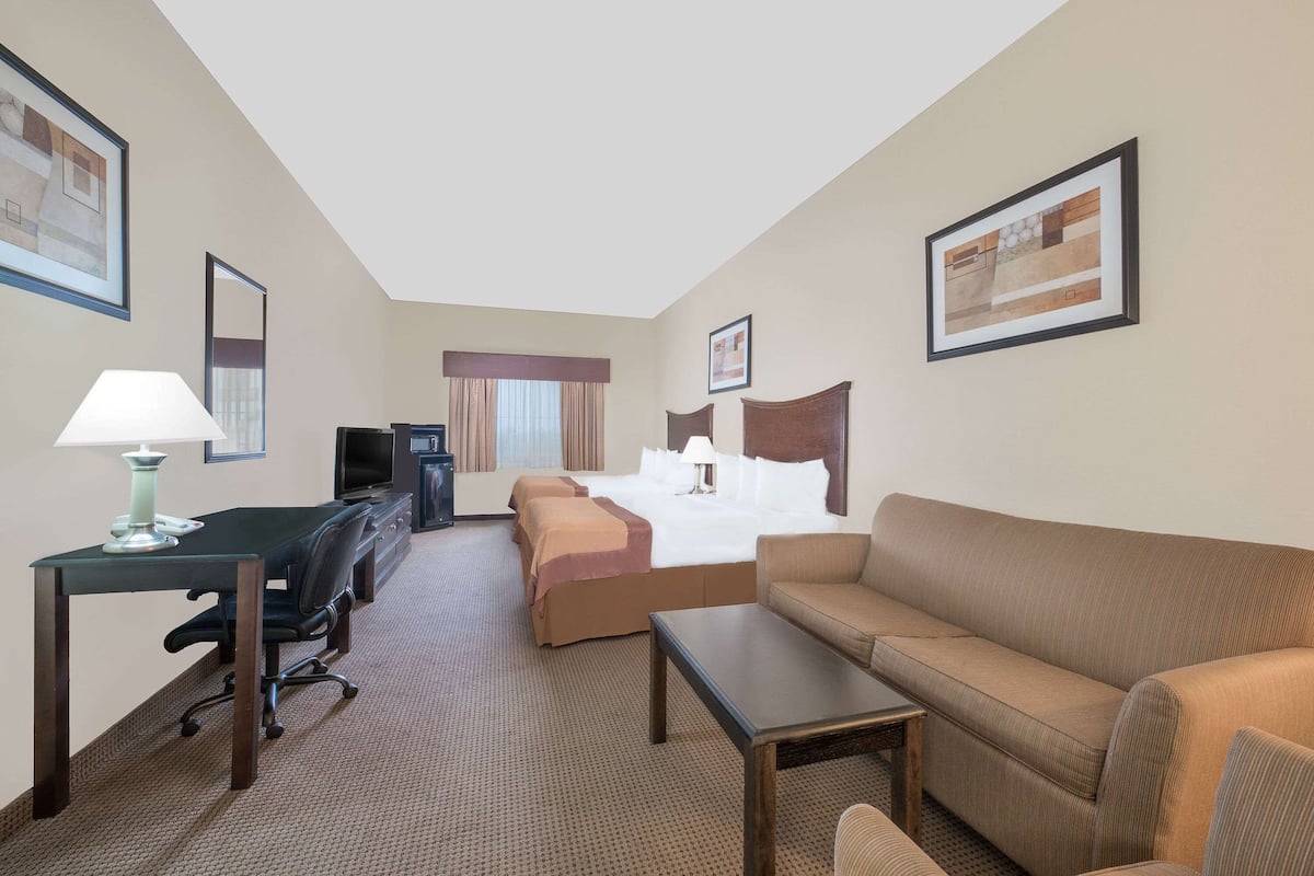 Een hotelkamer met een bed, een bank, een bureau met een lamp en een televisie.