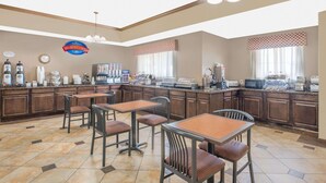A breakfast area with a counter, chairs, and kitchen appliances. - Baymont by Wyndham Snyder (Snyder)
