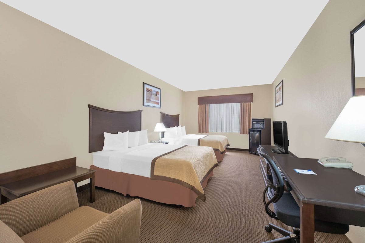 Een hotelkamer met twee bedden, een bureau, een stoel, een televisie en een bureaulamp.