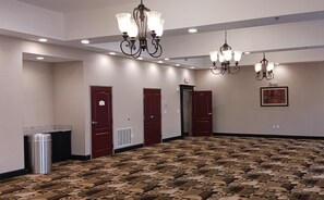 A hotel lobby with a patterned carpet, multiple doors, and chandeliers. - Red Roof Inn & Suites Longview (Longview)