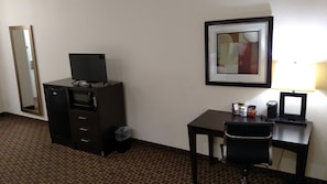 A hotel room with a desk, chair, a television on a cabinet, a framed picture on the wall, and a trash bin. - Red Roof Inn & Suites Longview (Longview)