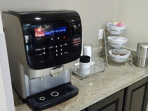 A Folgers coffee machine with a digital interface, a coffee dispenser, and a water dispenser. - Red Roof Inn & Suites Longview (Longview)