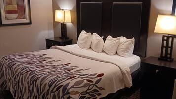Habitación de hotel con cama, dos lámparas de noche, una mesita de noche y un cuadro en la pared.