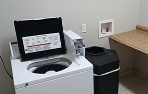 A front-loading washing machine with a control panel and a coin slot for payment. - Red Roof Inn & Suites Longview (Longview)