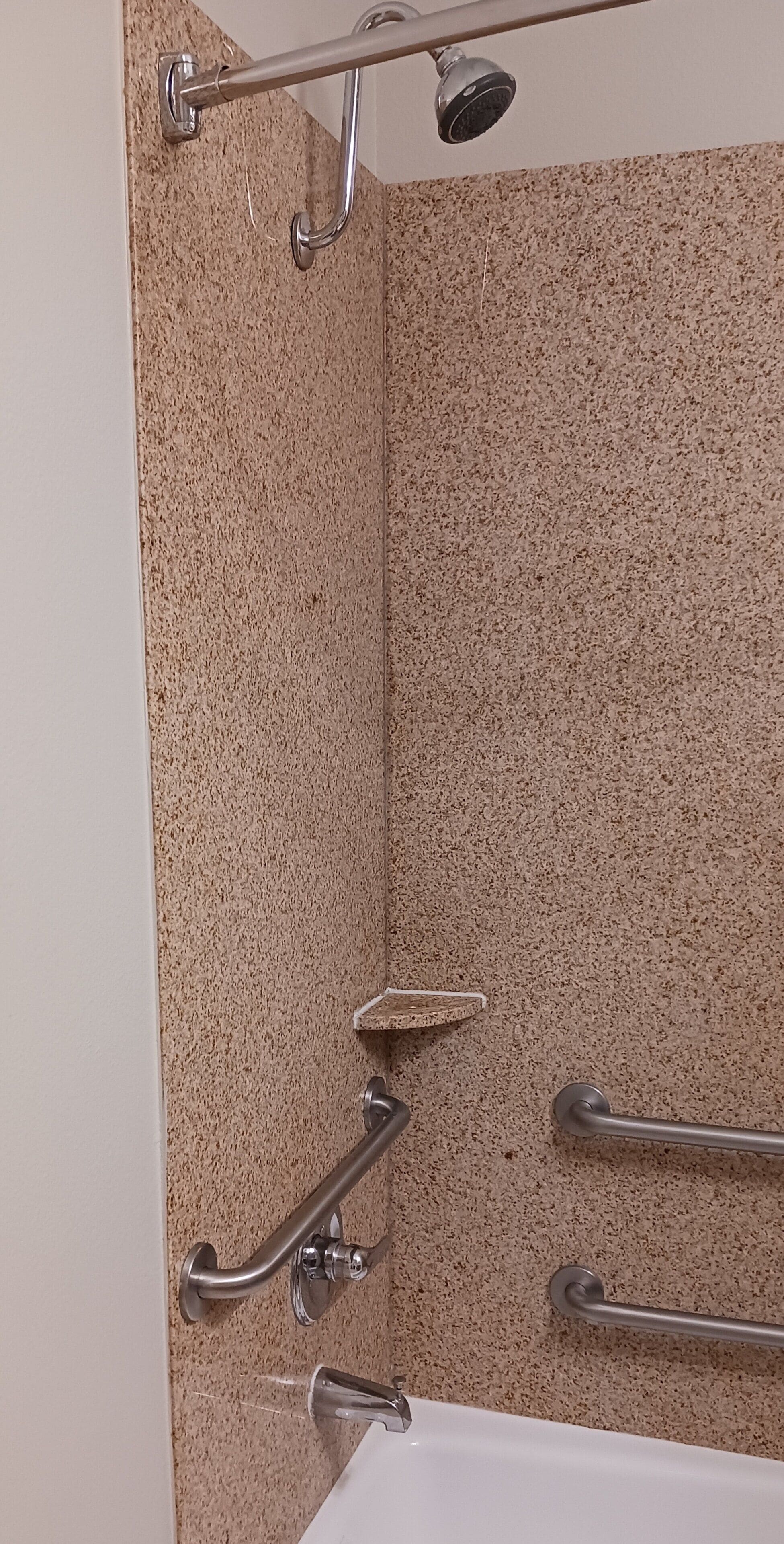 A bathroom with a shower, grab bars, and a bathtub.