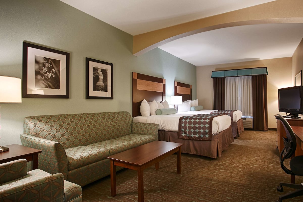 A hotel room with a sofa, a bed, a desk, and a TV.