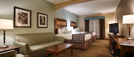 A hotel room with a sofa, a bed, a desk, and a TV.