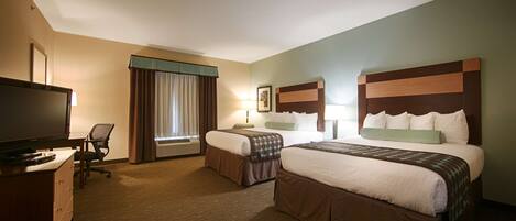 A hotel room with two beds, a desk with a television, and a chair.