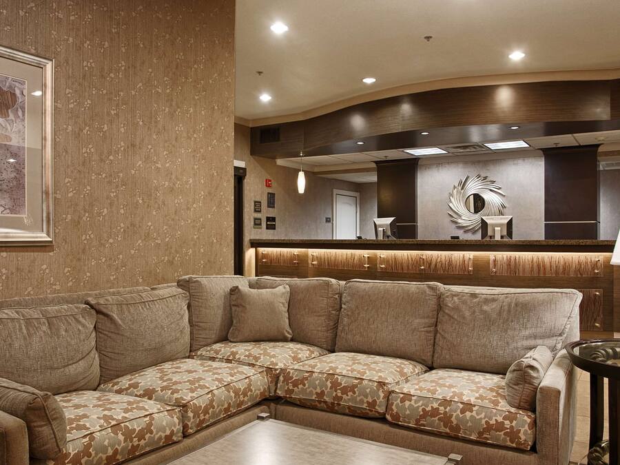 Un soggiorno moderno con un divano componibile, un tavolo rotondo in vetro e uno specchio decorativo.