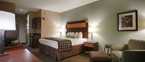 A hotel room with a bed, bedside tables, a desk, a chair, and a television.