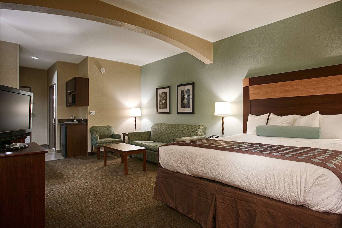 A hotel room with a large bed, a television, a desk, and two chairs.