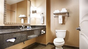 A modern bathroom with a granite countertop, a white toilet, a towel rack, and a mirror. - Best Western Plus Texarkana Inn & Suites (Texarkana)